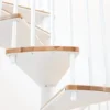 Detalle de peldaños en madera y estructura blanca de una escalera de caracol interior, con acabado moderno y minimalista.