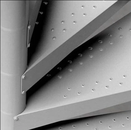 Detalle de peldaños antideslizantes en escalera de caracol metálica, diseño robusto ideal para exteriores y zonas de alto tránsito.