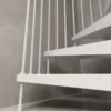 Detalle inferior de escalera de caracol blanca metálica, con estructura sólida y barandilla de seguridad para uso exterior.