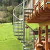 Escalera de caracol metálica galvanizada instalada en exterior, ideal para jardines, terrazas o accesos a viviendas elevadas
