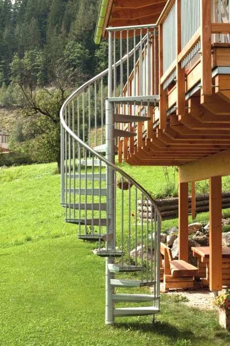 Escalera de caracol metálica galvanizada instalada en exterior, ideal para jardines, terrazas o accesos a viviendas elevadas